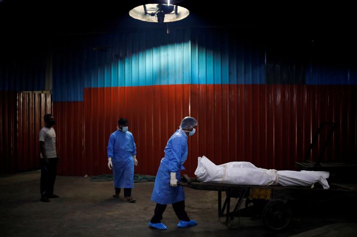 A health worker wearing personal protective equipment (PPE) carries the body of a man, who died due to the coronavirus disease (COVID-19), at a crematorium in New Delhi, India September 7, 2020. REUTERS/Adnan Abidi TPX IMAGES OF THE DAY