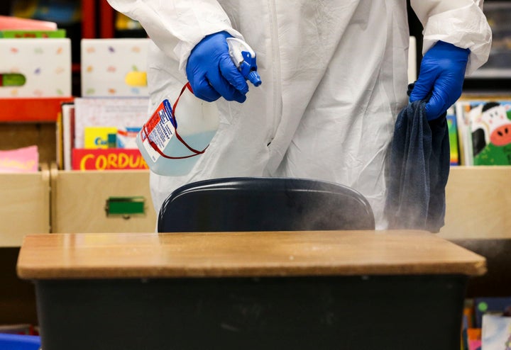 Ronnie Godby sprays disinfectant on desks and chairs as he and the other school custodians clean a classroom at Richard A. Simpson Elementary School in Arnold on Thursday, Nov. 5, 2020. The school went to fully virtual learning on Monday, Nov. 2 after more than 5% of the staff and students tested positive for COVID-19, they will stay virtual until Monday Nov.16 after ten work days. (Colter Peterson/St. Louis Post-Dispatch via AP)