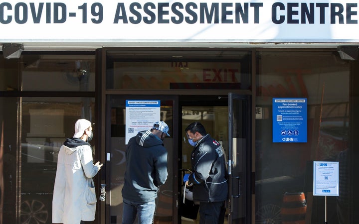 A security officer wearing a face mask and a face shield checks a person's appointment at a COVID-19 assessment centre in Toronto, Ont., on Nov. 12, 2020. 