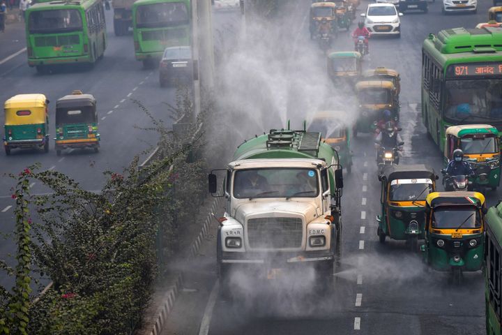 An East Delhi Municipal Corporation (EDMC) vehicle sprinkles water to control dust as commuters drive along a road amid smoggy conditions in New Delhi on November 15, 2020. (Photo by Prakash SINGH / AFP) (Photo by PRAKASH SINGH/AFP via Getty Images)
