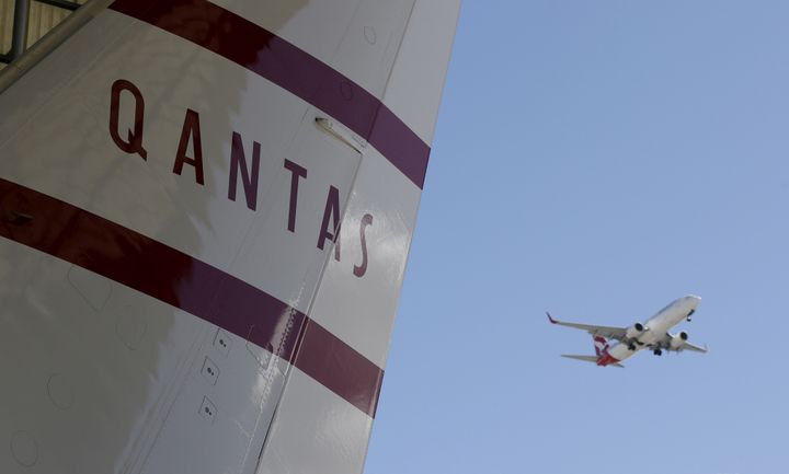 A Qantas jet (R) flies past the tail section of a Boeing 737-800 painted in Qantas' 1959 retro colour scheme during an event marking the 95th anniversary of the Airline at the Qantas Hangar at Sydney International Airport, Australia, November 16, 2015. 