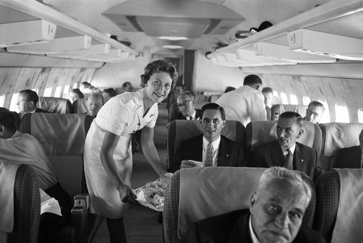 An air stewardess serving food to passengers on board a Qantas Boeing 707 plane at London airport, August 1959. 