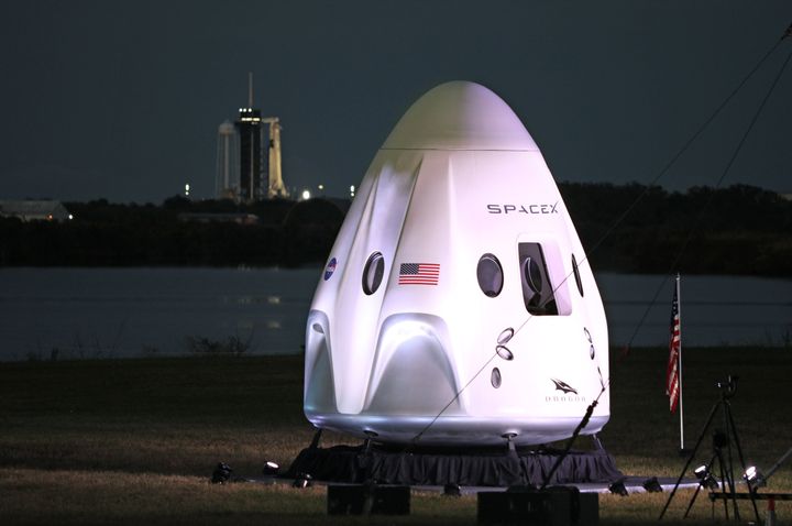 A full-size model of the Crew-1 spacecraft module sits near the launch pad as a SpaceX Falcon 9 rocket is seen at launch complex 39A in the distance at the Kennedy Space Center in Florida on November 15, 2020. 