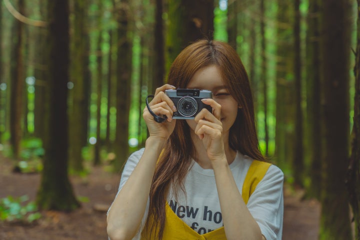 A woman taking pictures of beautiful nature with camera