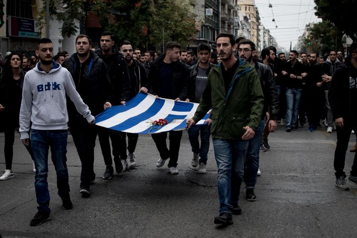Students wear a blood-stained Greek flag with roses, which was in the National Technical University in Athens, Greece on November 17, 2019 during a demonstration on the 46th anniversary of Polytechnic school, uprising against the military Junta that was ruling Greece in 1993. (Photo by Nikolas Kokovlis/NurPhoto via Getty Images)