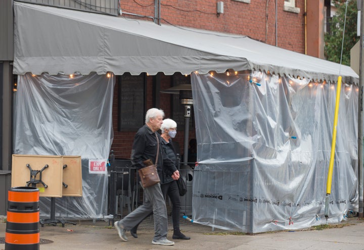 Pedestrians walk by a tented patio on Bloor Street in Toronto.