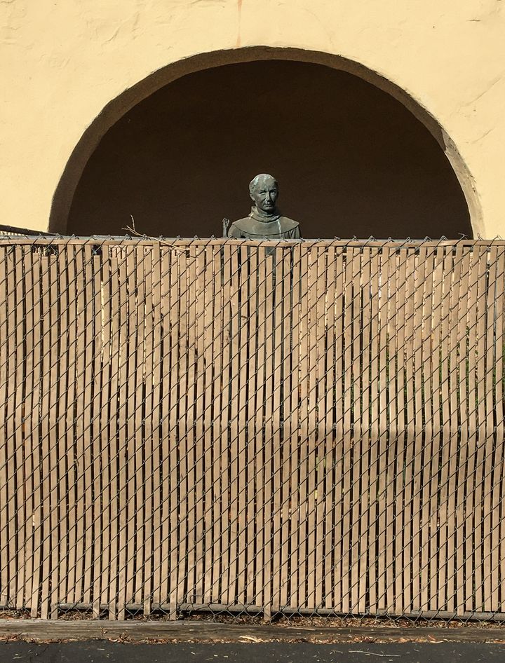 A bronze statue of St. Junípero Serra, located at the entrance to the Old Mission Santa Ines in Solvang, California, is surrounded by a chainlink fence to protect it on Nov. 2, 2020.