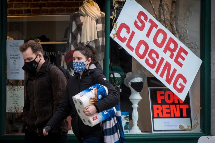 People wears masks as they walk past a store that is closing in Kingston, Ont. on Nov. 16, 2020, as the COVID-19 pandemic continues across Canada and around the world.