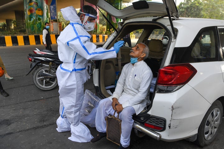 A medical worker collects a nasal swab sample from a man for a Rapid Antigen Test (RAT) for the Covid-19 coronavirus at Delhi-Uttar Pradesh border in Noida on November 18, 2020.