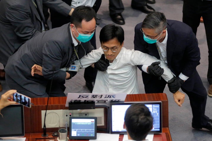 Then pan-democratic legislator Eddie Chu, center, is taken away by security guards during a Legislative Council's House Committee session in Hong Kong on May 8, 2020. 