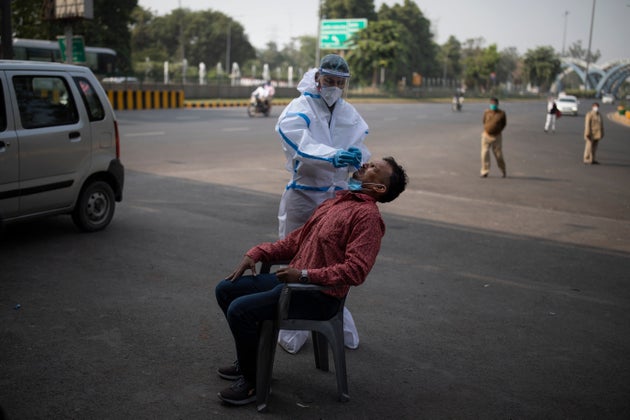 A health worker takes a nasal swab sample of a man to test for Covid-19 during random testing of people...