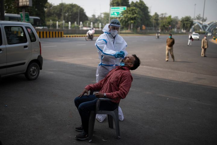 A health worker takes a nasal swab sample of a man to test for Covid-19 during random testing of people at Delhi-Noida border on November 18, 2020. 