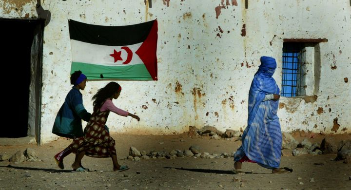 Una mujer y unos niños saharauis pasan ante una bandera, en un campo de refugiados de Samra, Argelia, en 2003.