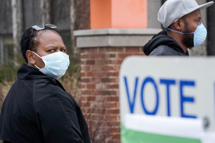 Voters masked against the coronavirus line up to vote at Riverside High School in Milwaukee.