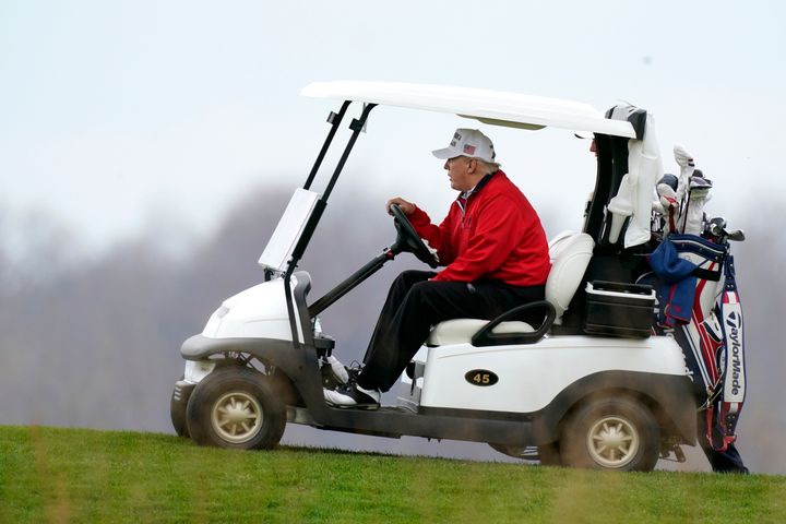 Trump drives a golf cart at Trump National Golf Club on Saturday.