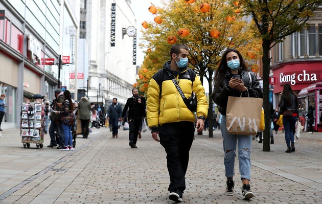 People wearing face masks walk down Market Street, Manchester.