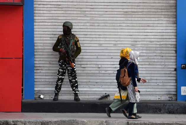 Kashmiri girls walk past a paramilitary soldier in Srinagar on October 31, 2020. Most of the shops and...