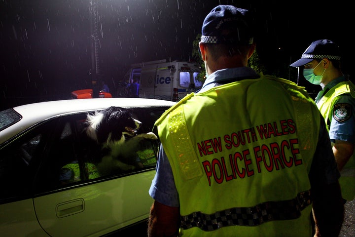 NSW police greet a dog in a vehicle stopped at the border checkpoint at South Albury as they prepare to reopen on November 23, 2020 in Albury, Australia. The New South Wales reopened its border to Victoria at 12:01 on Monday 23 November, with people able to freely travel into NSW for the first time since border restrictions were put in place in July due to Victoria's second wave COVID-19 outbreak. (Photo by Lisa Maree Williams/Getty Images)