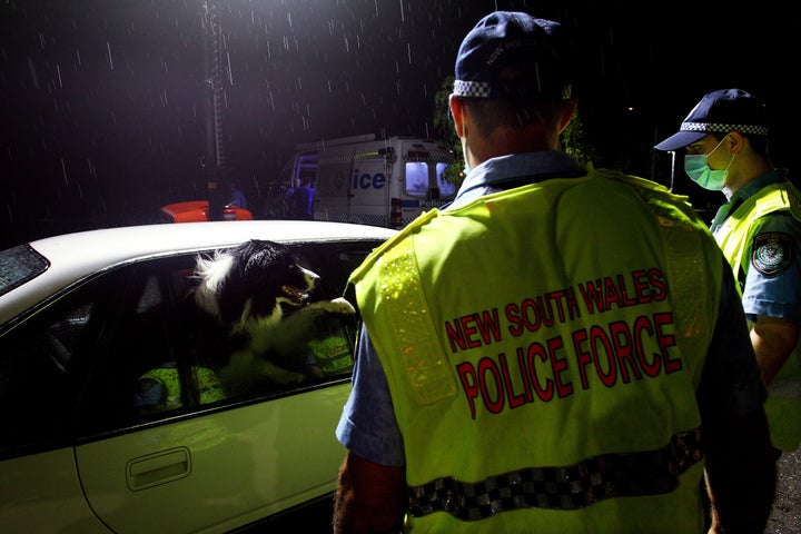 NSW police greet a dog in a vehicle stopped at the border checkpoint at South Albury as they prepare to reopen on November 23, 2020 in Albury, Australia. The New South Wales reopened its border to Victoria at 12:01 on Monday 23 November, with people able to freely travel into NSW for the first time since border restrictions were put in place in July due to Victoria's second wave COVID-19 outbreak. (Photo by Lisa Maree Williams/Getty Images)