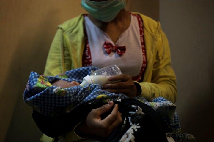 A 17-year-old mother gives a bottle to her 2-week-old baby, whom she says was born as a result of a rape in Sumatra, Indonesia, Sunday, Sept. 9, 2018. She started working on a plantation as a young child to help her family survive, never going to school or learning how to read or write. One day she said her boss took her alone to a quiet part of the estate. After the attack, while still half-naked, she said the man held a blade to her throat. "He threatened to kill me with an ax. ... He threatened to kill my whole family." Then, she said, he stood up, spit on her and walked away.