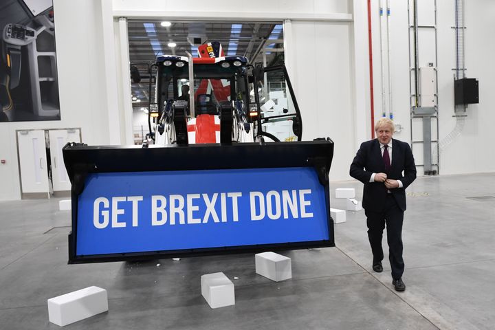 Prime Minister Boris Johnson walks away after driving a Union flag-themed JCB, with the words "Get Brexit Done" inside the digger bucket, through a fake wall emblazoned with the word "Gridlock"