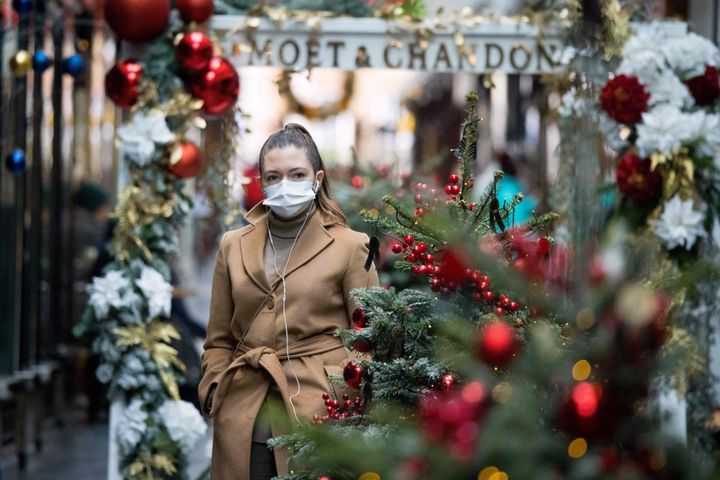 A pedestrian wearing a face mask walks past Christmas-themed window displays inside Burlington Arcade in central London on Monday