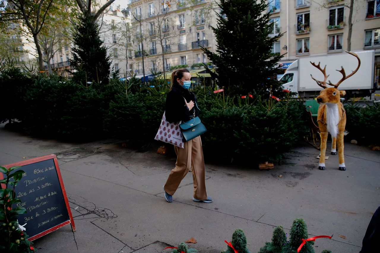 A woman walks past Christmas trees at florist in Paris on Friday. The number of new coronavirus infections in France rose by 17,881 on Saturday, lower than the 22,882 reported on Friday, while the number of people hospitalized with COVID-19 dropped for the fifth day in a row.