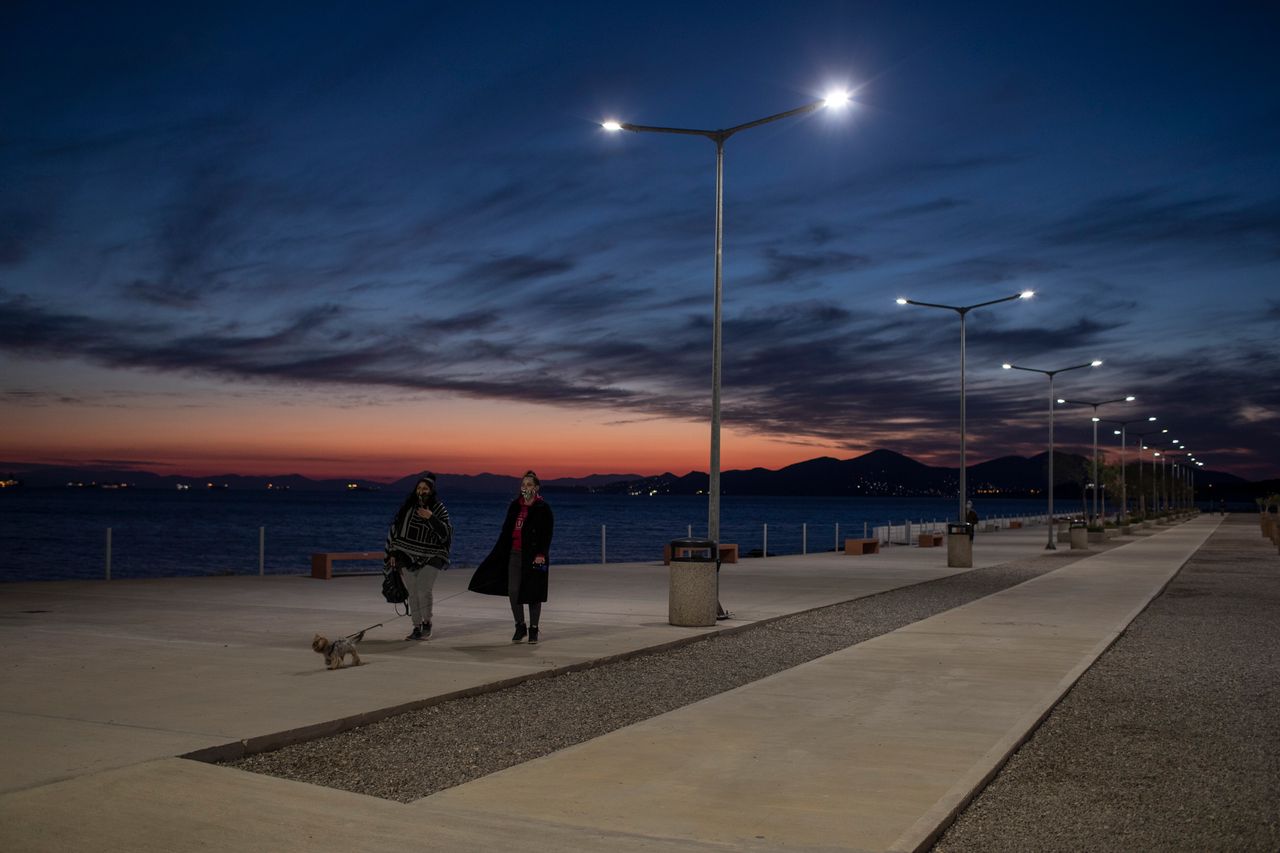 People walk by the seain Drapetsona suburb of Piraeus, near Athens, on Monday. A second nationwide lockdown is in place until the end of November, but the restrictions are widely expected to be extended into December in some form.