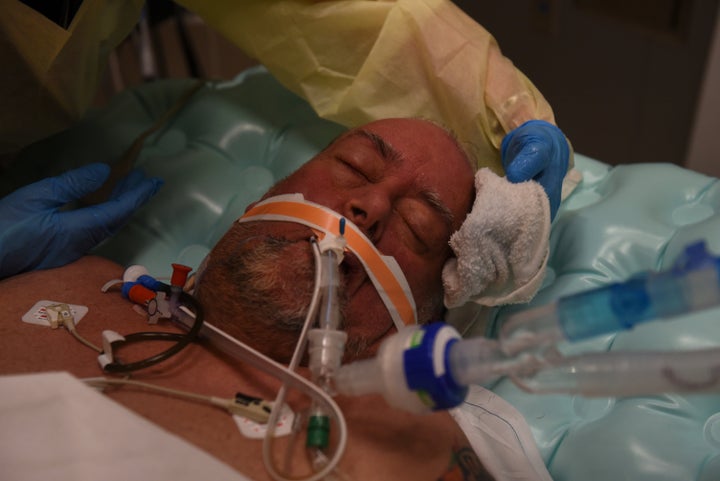 Healthcare personnel treat Daniel Benewiat, a patient who is on a ventilator, inside a room for patients with COVID-19 at a h