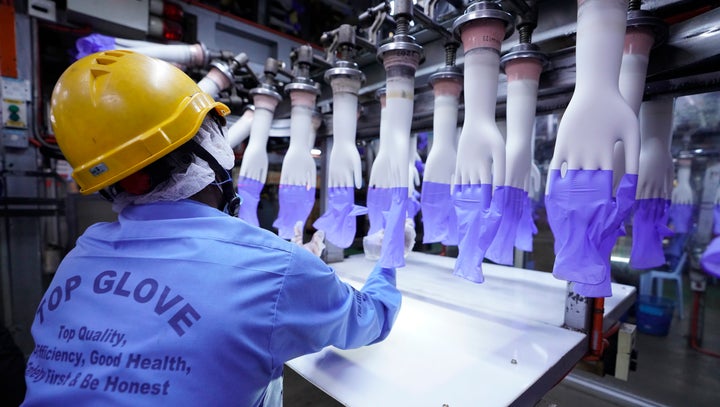 In this Aug. 26 file photo, a worker inspects disposable gloves at the Top Glove factory in Shah Alam on the outskirts of Kua