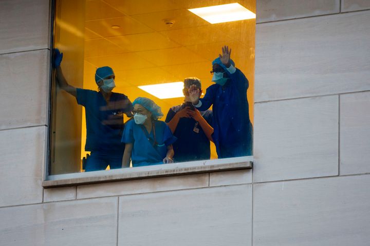 Health-care workers watch from behind a window at Toronto General Hospital as Toronto first responders parade down hospital row in Toronto, Ont., on April 19, 2020.
