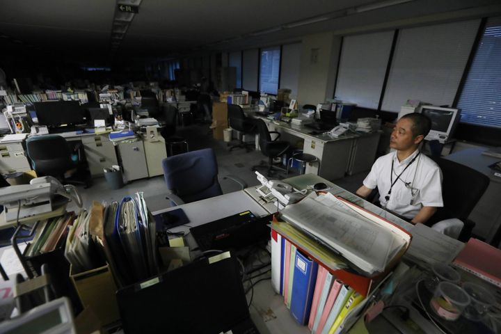 暗くなったオフィスで帰り支度をする厚生労働省の職員（資料写真）