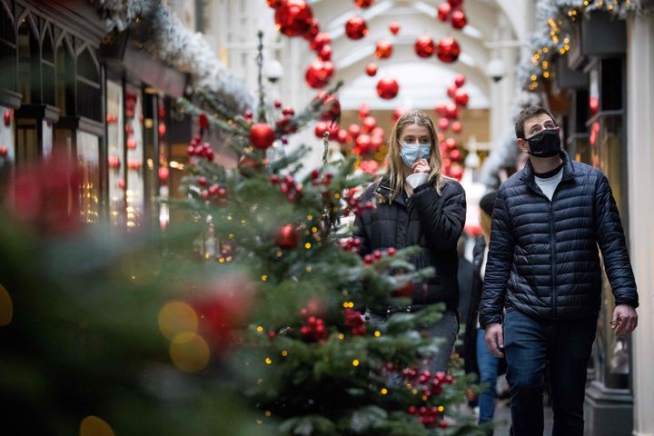 Pedestrians wearing face masks walk past Christmas-themed window displays inside Burlington Arcade in central London, on November 23.
