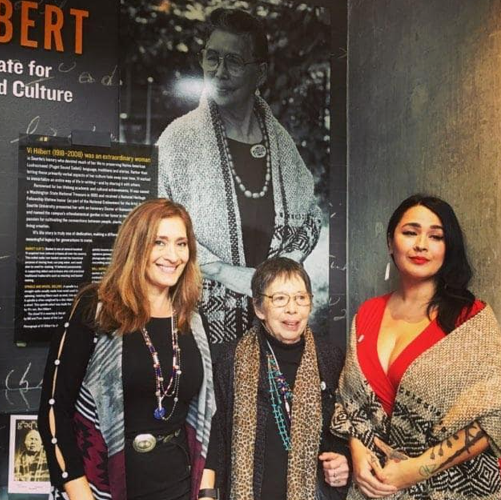 Four generations together at Seattle University in 2020. From left, Jill LaPointe (the author's mom), Lois Dodson (the author's grandmother), and the author. Vi taqʷšəblu Hilbert (the author's great-grandmother) is in the painting behind them.