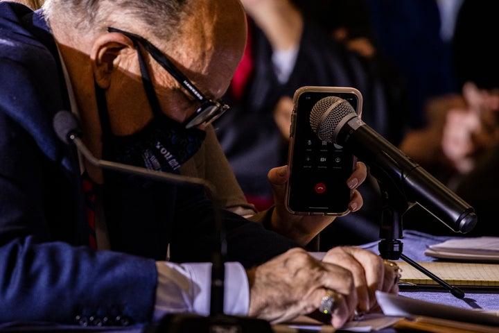 <strong>Rudy Giuliani listens as Jenna Ellis, both members of Donald Trump's legal team, holds up a cell phone to the microphone so Trump can speak during a Pennsylvania Senate committee hearing.</strong>