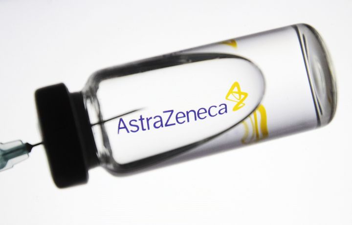 UKRAINE - 2020/11/24: In this photo illustration a medical syringe and a vial with fake coronavirus vaccine seen in front of the AstraZeneca BritishSwedish multinational pharmaceutical logo. (Photo Illustration by Pavlo Gonchar/SOPA Images/LightRocket via Getty Images)