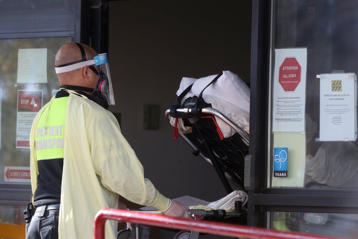 Employees of a stretcher service wear personal protective gear as they return a resident to Parkview Place personal care home in Winnipeg, on Nov. 2, 2020.