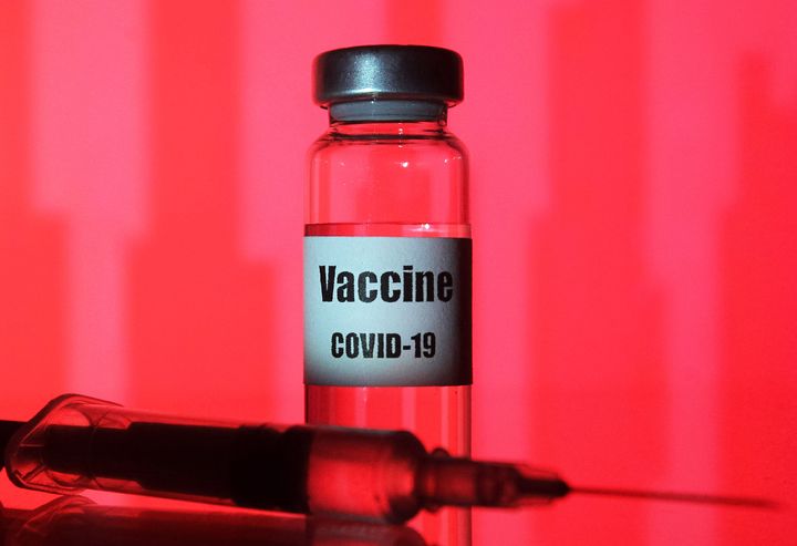 UKRAINE - 2020/11/22: In this photo illustration a medical syringe and a vial with COVID-19 coronavirus vaccine seen on red background. (Photo Illustration by Pavlo Conchar/SOPA Images/LightRocket via Getty Images)
