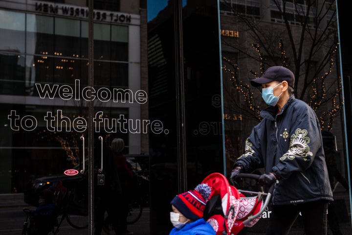 A masked pedestrian passes a business with the words, "Welcome to the future" on the front door on Nov. 20, 2020.