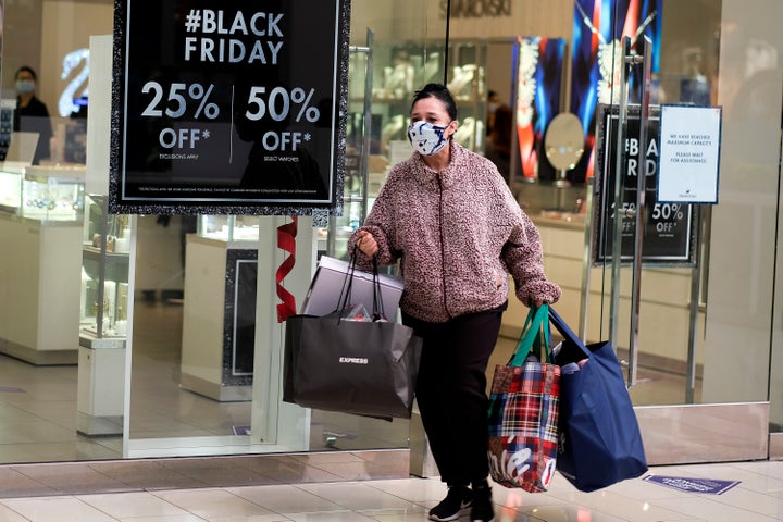 A Black Friday shopper wearing a face mask carries bags at the Glendale Galleria in Glendale, Calif., Friday, Nov. 27, 2020. (AP Photo/Ringo H.W. Chiu)