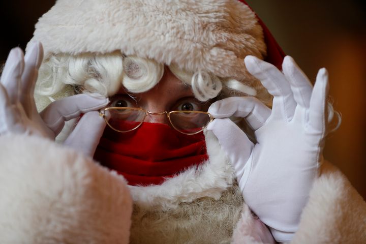 A Santa adjusts his glasses over a face mask as he attends a socially distanced Santa school training at Southwark Cathedral in London