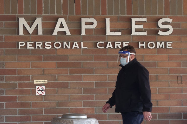 A man wearing a mask and face shield walks past the Maples Personal Care Home in Winnipeg, Man., on Nov. 2, 2020.