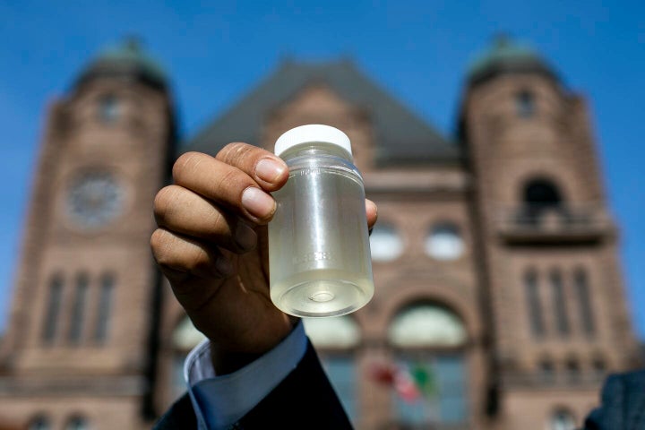 Kiiwetinoong MPP Sol Mamakwa holds up water collected from Neskantaga First Nation, where residents were evacuated over tainted water last month, during a rally at Queen’s Park in Toronto on Nov. 6, 2020.