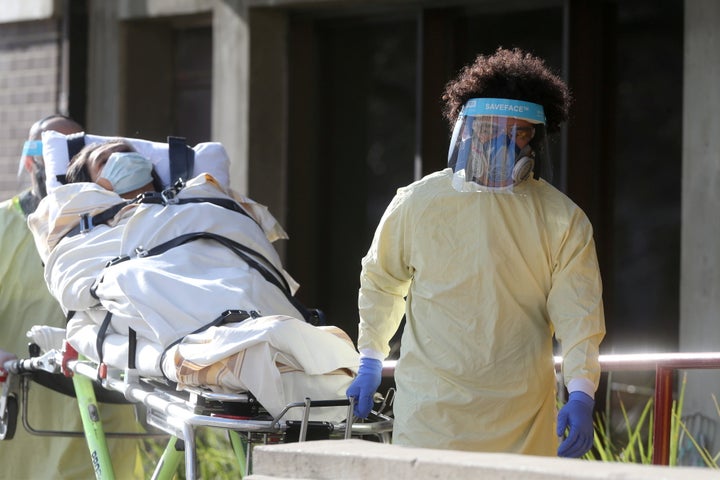 Employees of a stretcher service wear personal protective gear as they return a resident to Parkview Place personal care home, which is experiencing an outbreak of the coronavirus disease (COVID-19), in Winnipeg on Nov. 2, 2020.