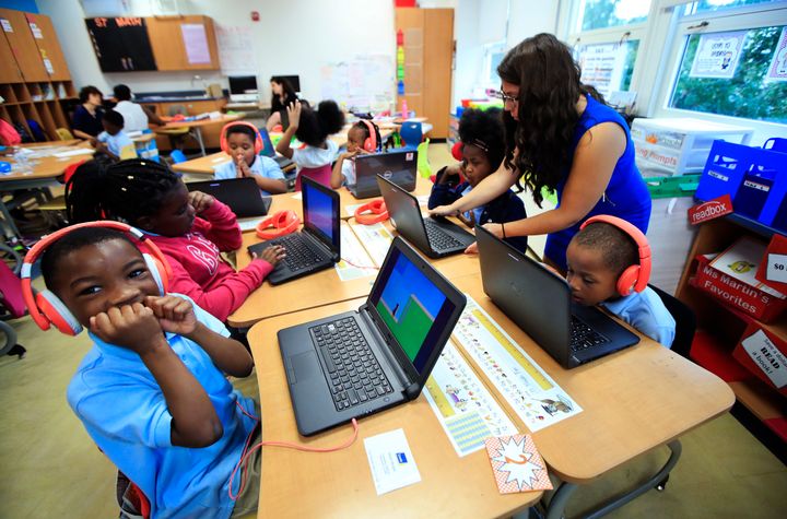 Second grade student Khalil Morgan, left, reacts after completing an interactive math problem solving on his computer in teacher Jillian Martin, standing right, math class at Turner Elementary School in southeast Washington, Aug. 29, 2017. Student Noah Fox, right, looks at his computer at right.