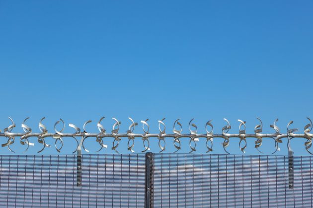 Restricted area.  Close up of a silver colored razor wire security fence against a blue sky