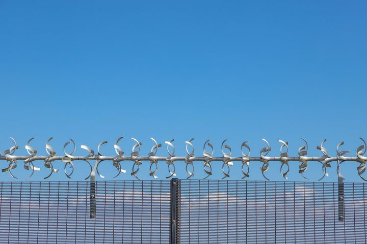 Restricted area. Close up of a silver colored razor wire security fence against a blue sky