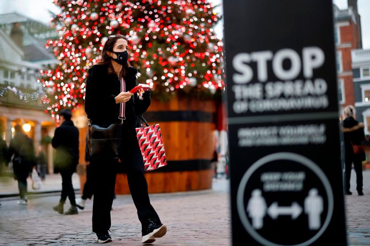 A pedestrian wearing a protective face covering walks past the Christmas tree in Covent Garden in central London on November 27