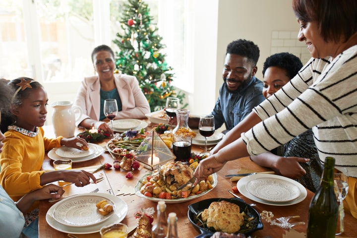 Woman cutting meat for family and friends on dining table at home during Christmas