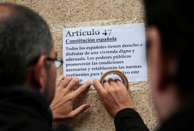 Un activista antidesahucios coloca en Madrid un cartel con el artículo de la Constitución...
